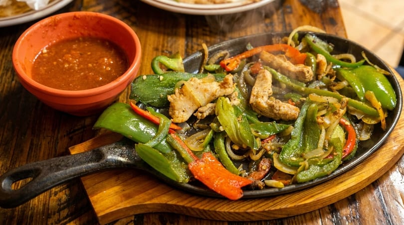 Sizzling chicken fajitas with green and red peppers, onions, and a side of salsa.